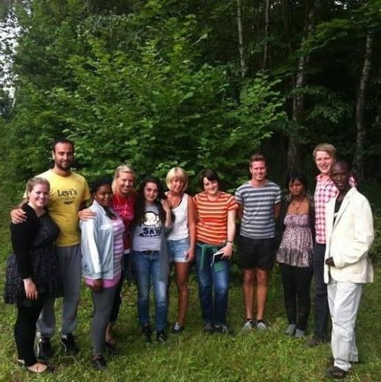 Eleven people pose together in front of trees.