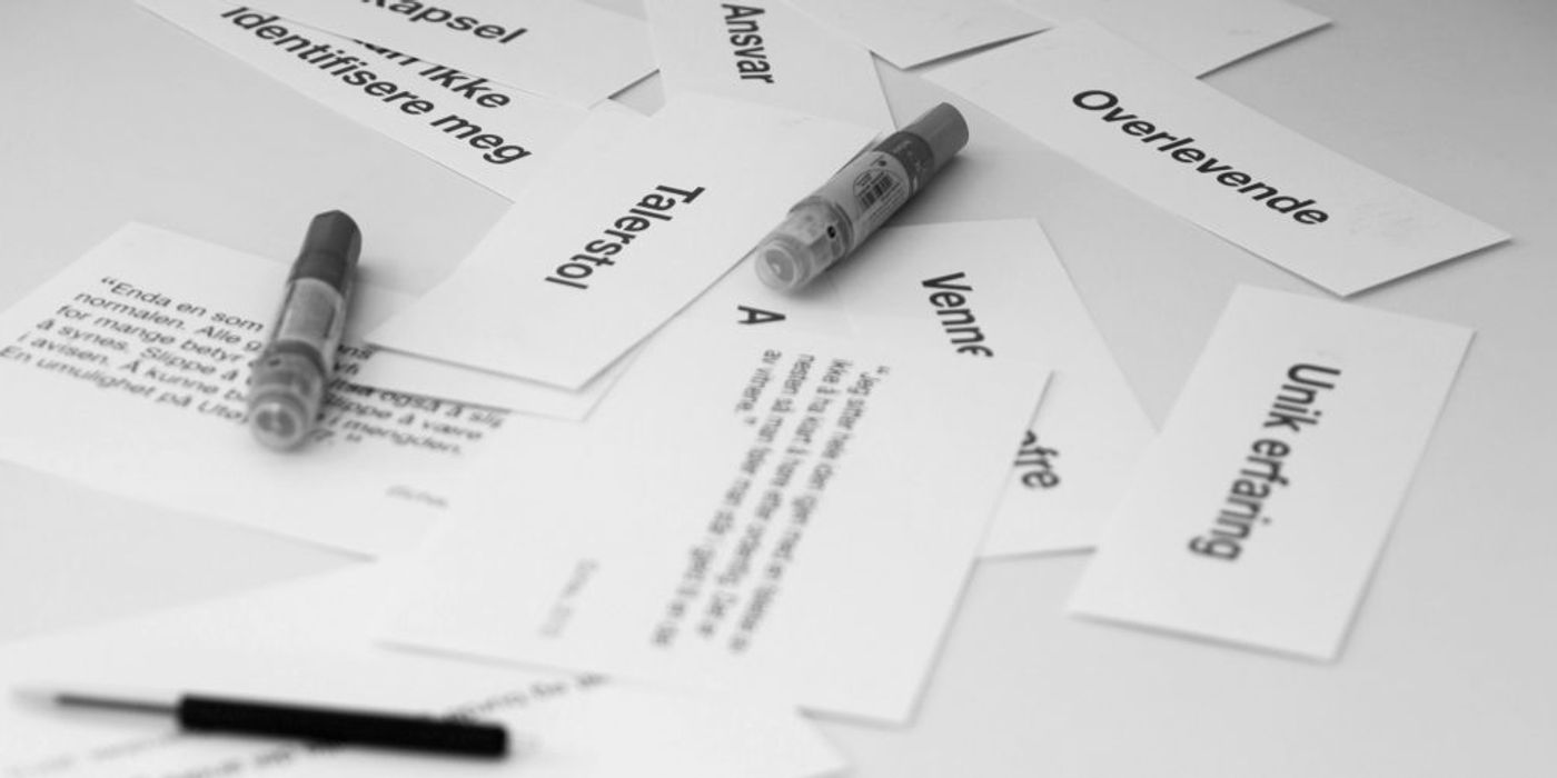 Black and white photo of notes with text on and pens lying on a table. 