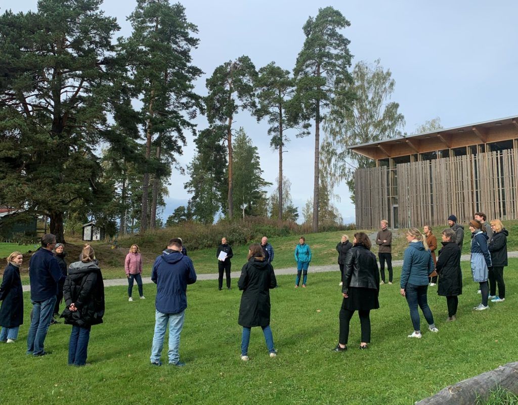 Adults gathered in a circle in front of Hegnhuset at Utøya.