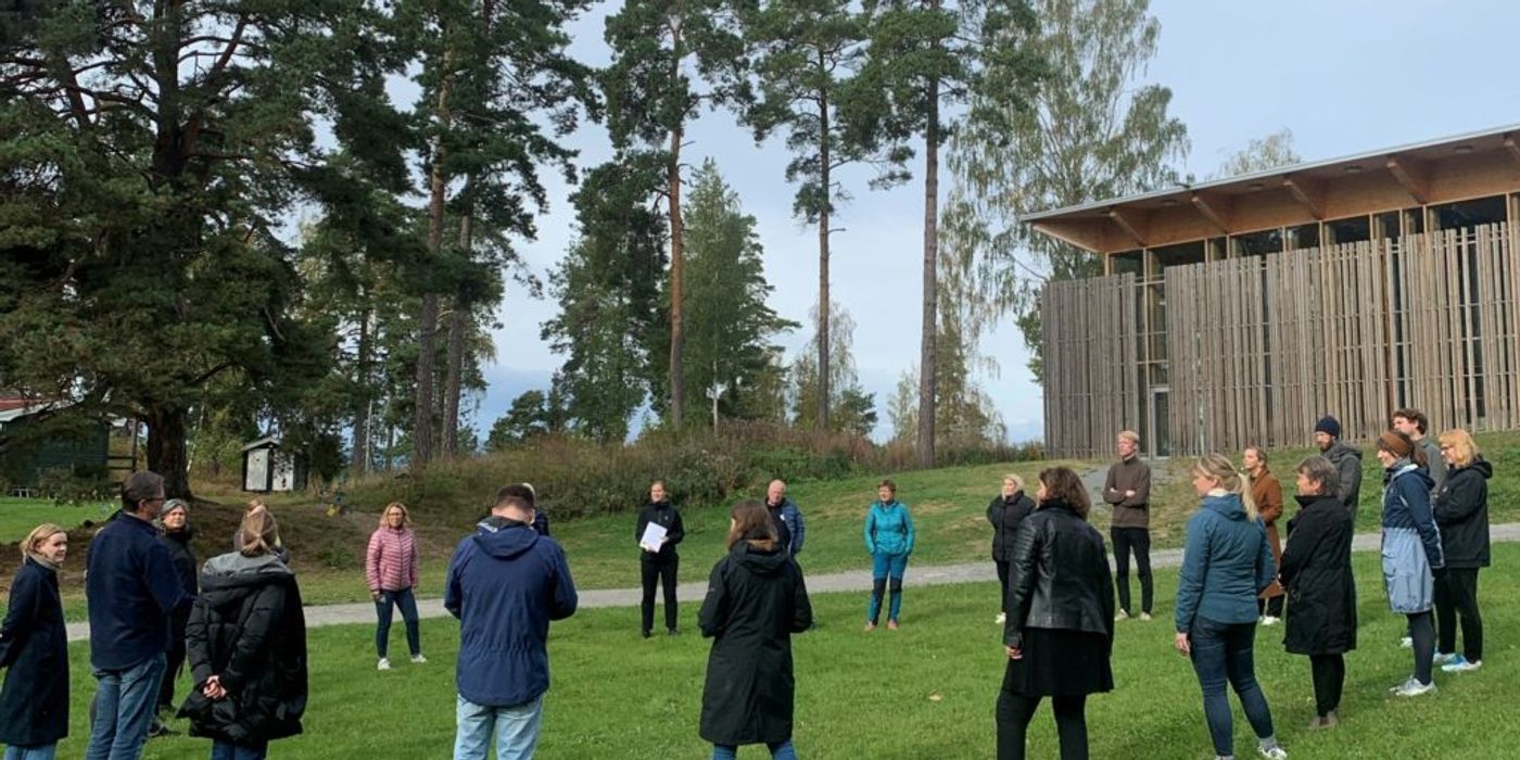 Adults gathered in a circle in front of Hegnhuset at Utøya.