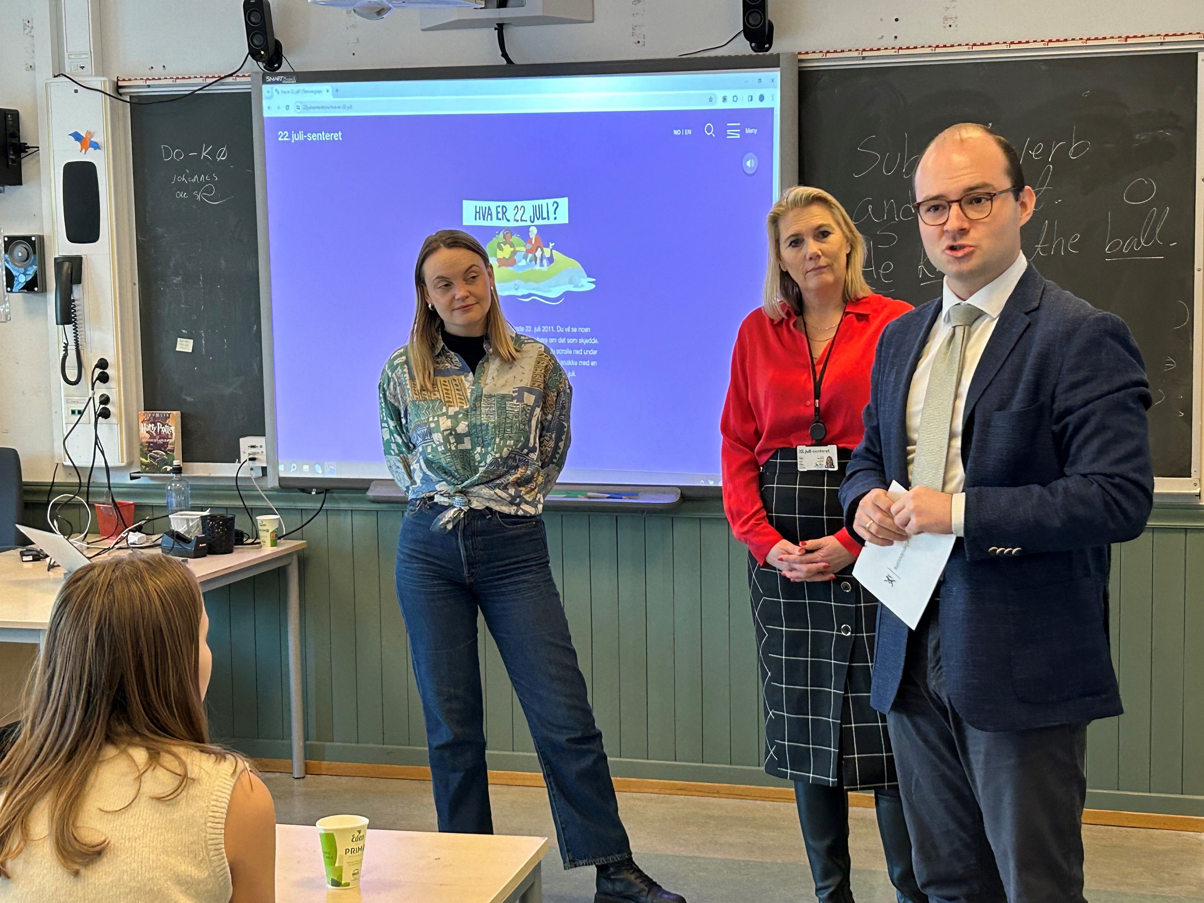 Tre personer foran en krittavle snakker til elever.