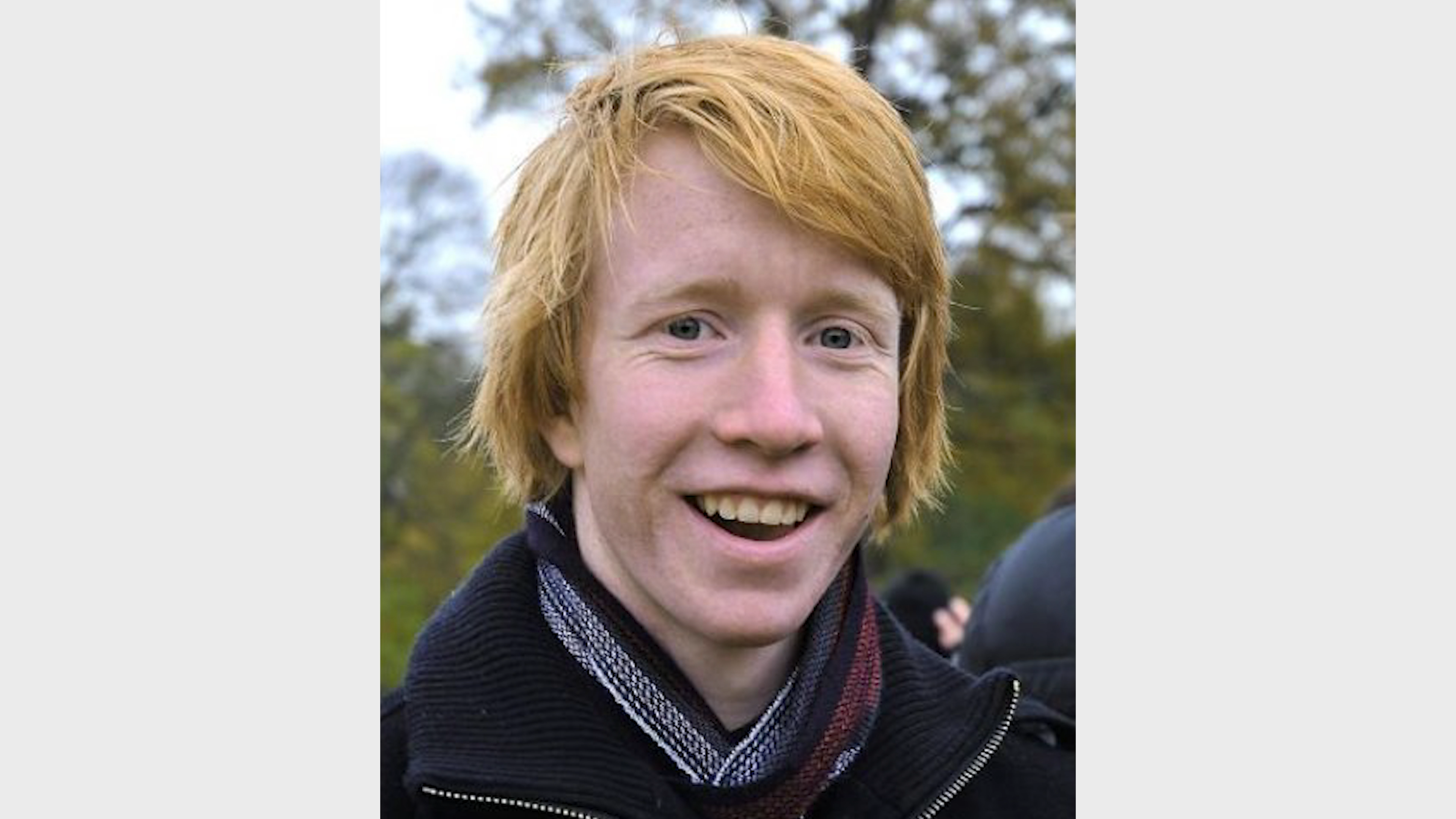 Portrett av en smilende ung med rødt hår.