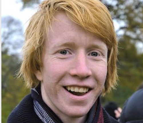 Portrett av en smilende ung med rødt hår.