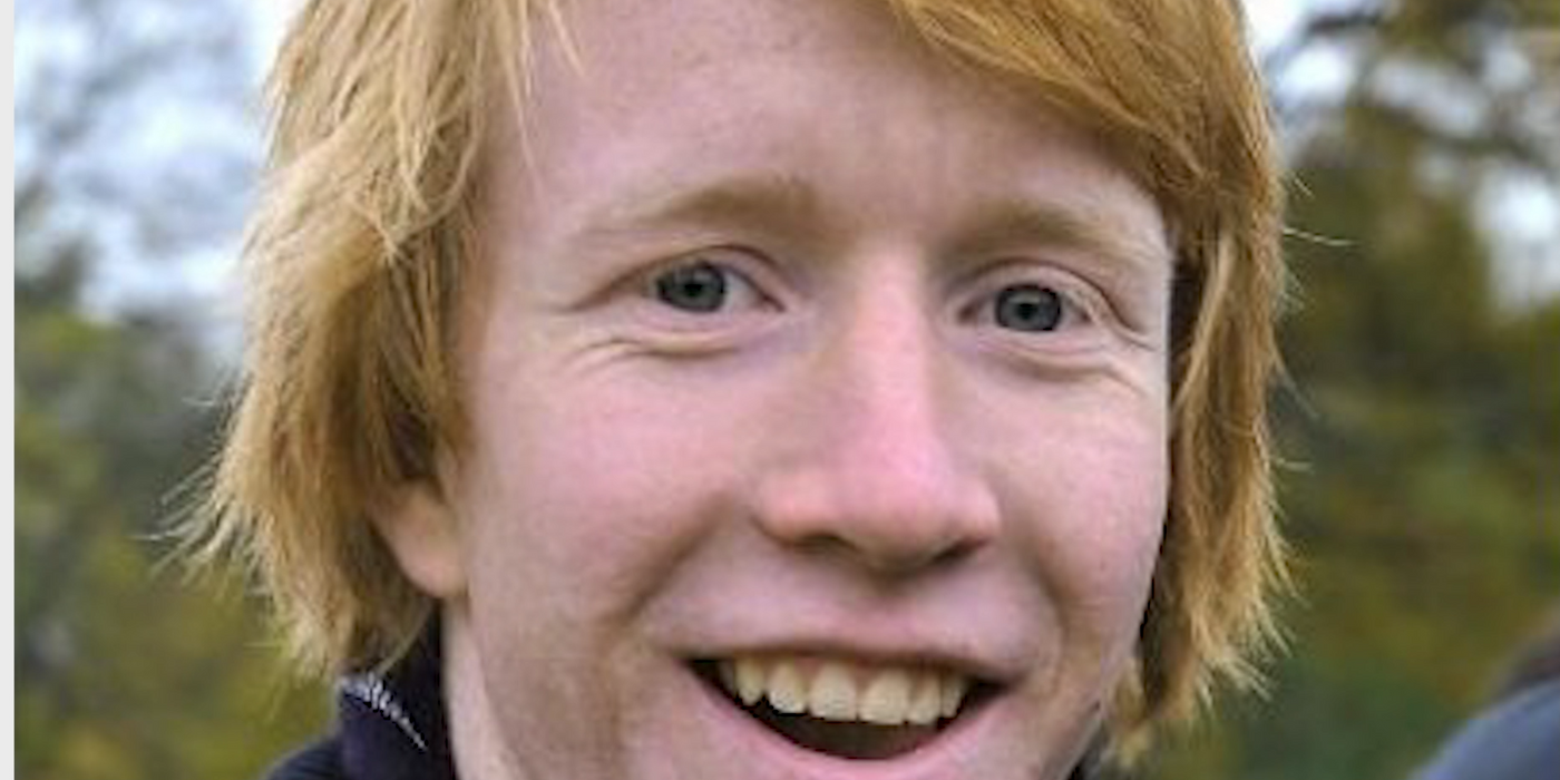 Portrett av en smilende ung med rødt hår.