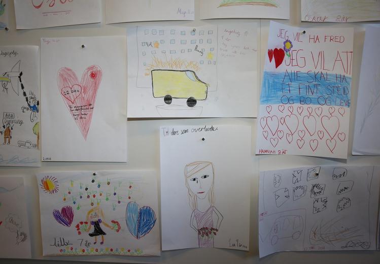 Children's drawings hanging on a wall. Hearts and other motifs.