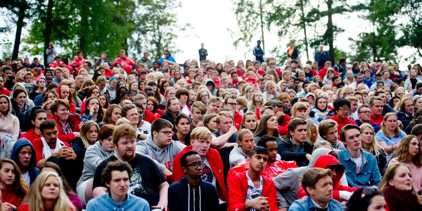 Mange mennesker med røde t-skjorter sitter samlet og ser fremover 