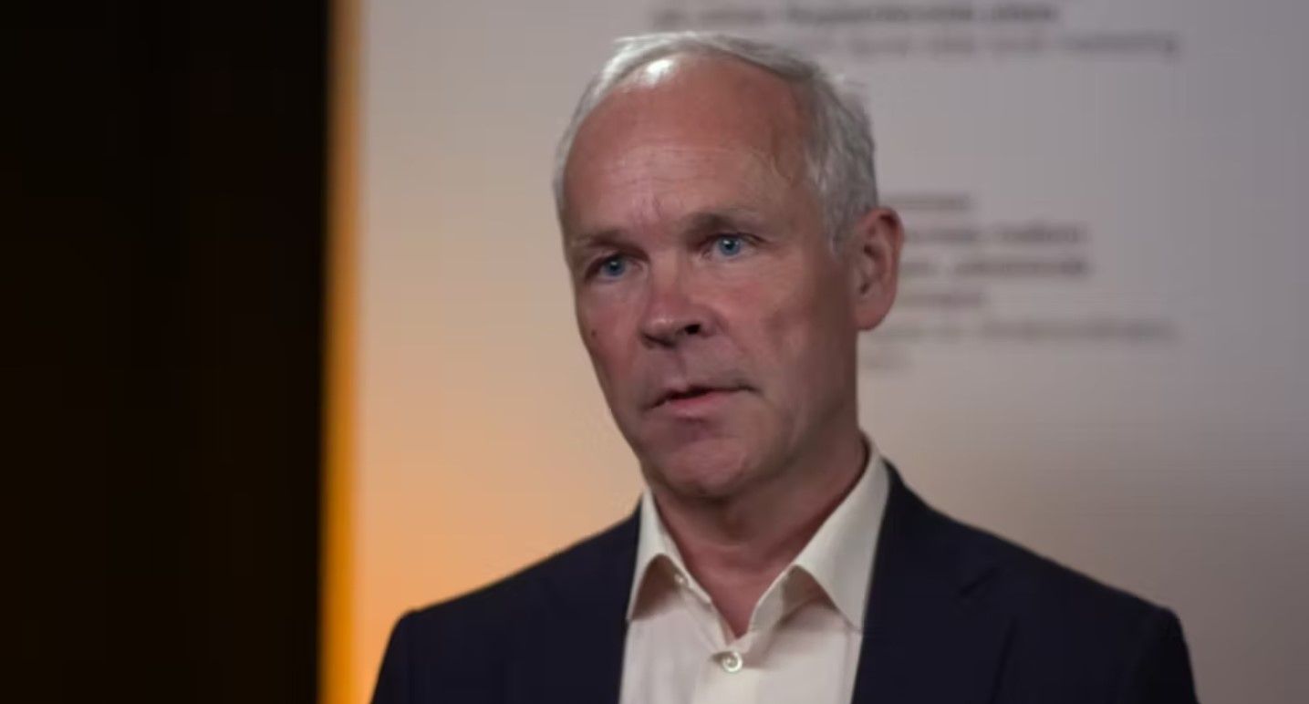 Man in  black suit talking. Blurred backgorund.