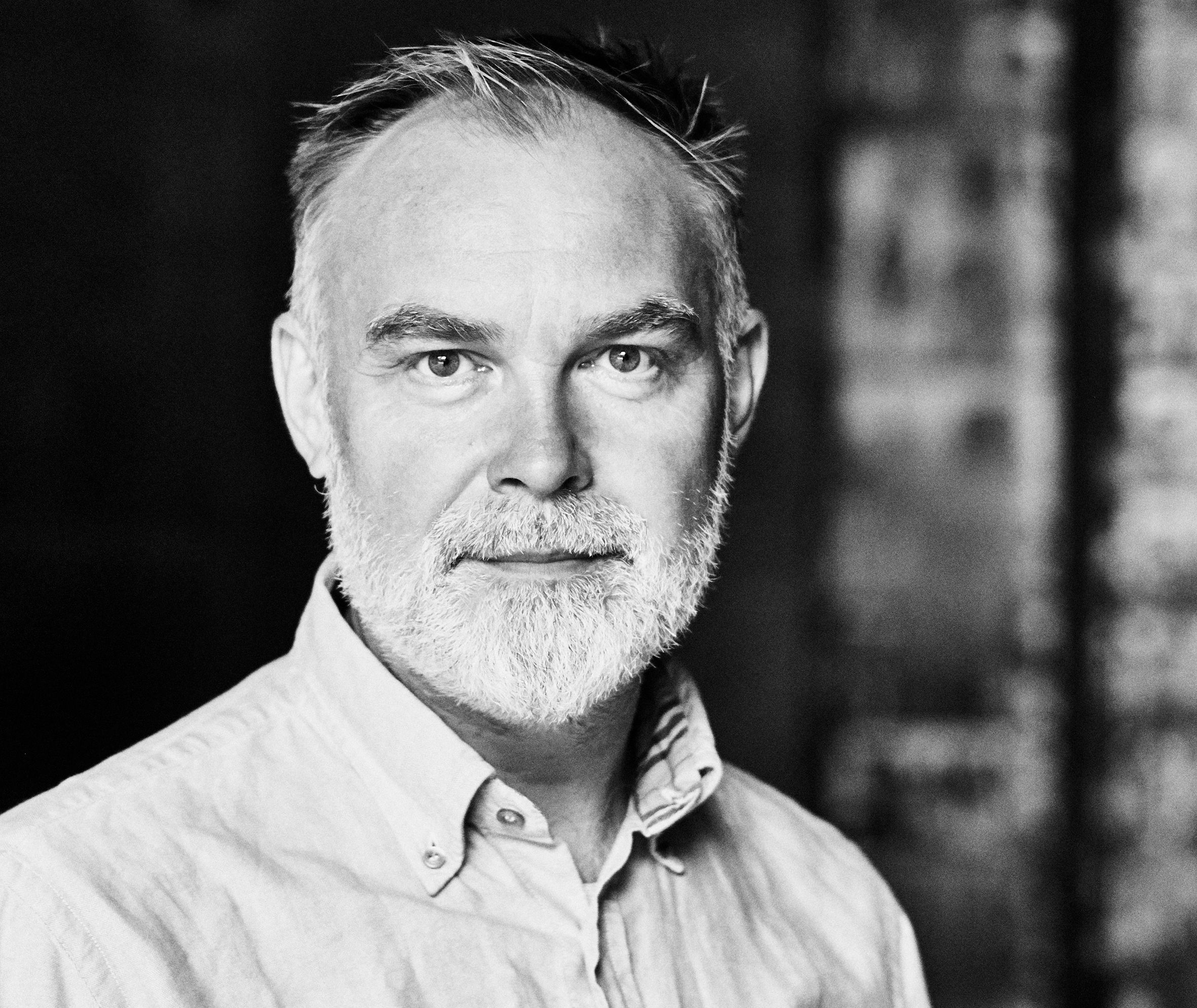 Portrett i sort og hvit av en mann med hvitt skjegg.    