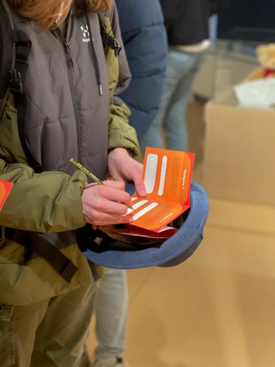 Close-up of a person writing in an orange brochure. 