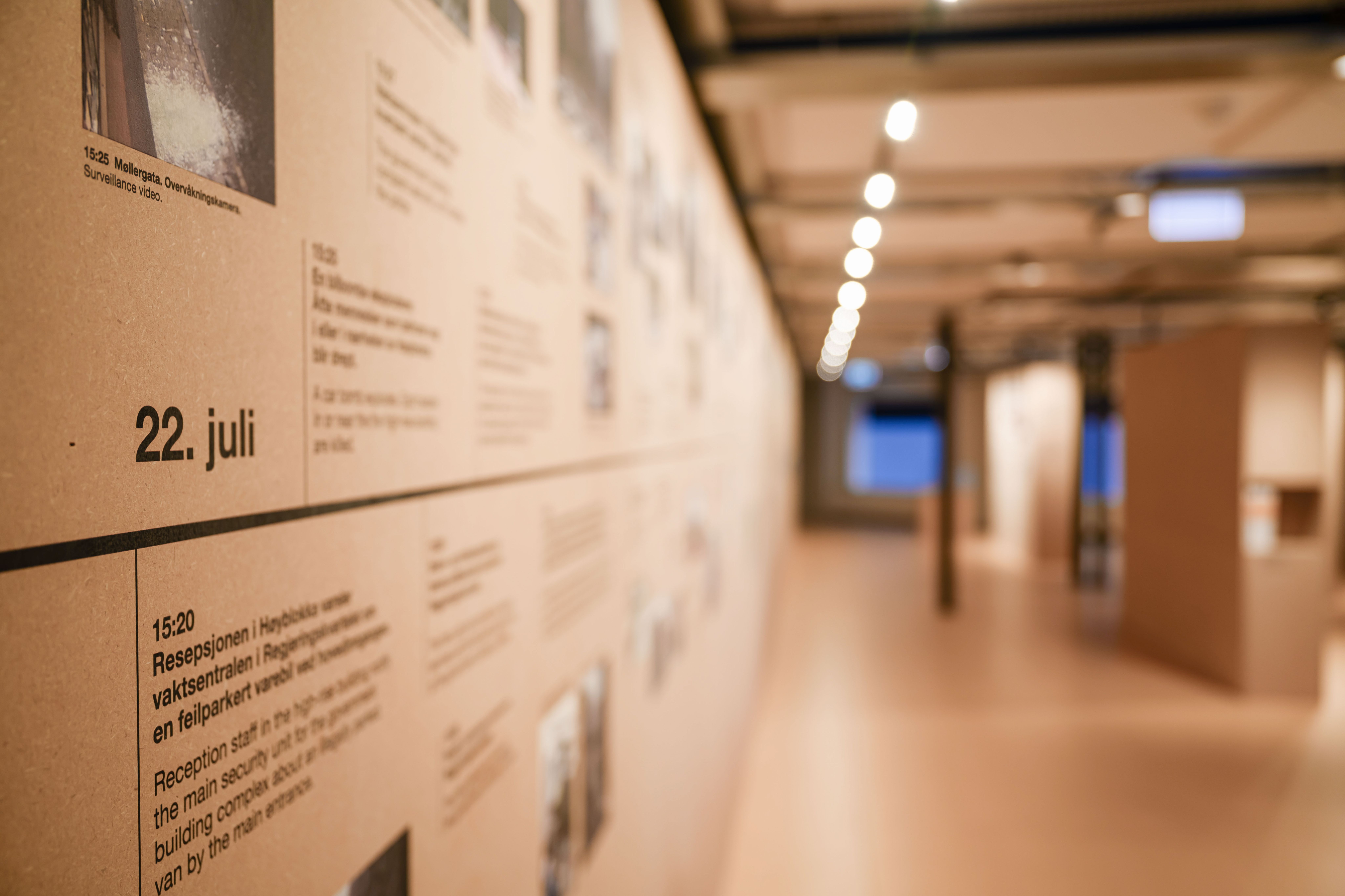 An exhibition wall with a timeline that is only in focus on the foreground, where one can read "22 July".