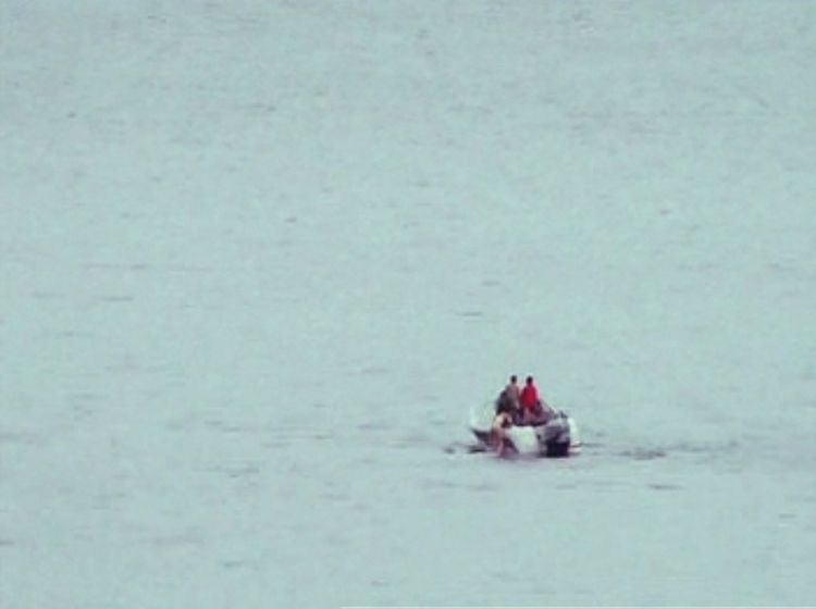 Uskarpt bilde av motorbåt med to personer. Vann rundt dem dekker resten av motivet.