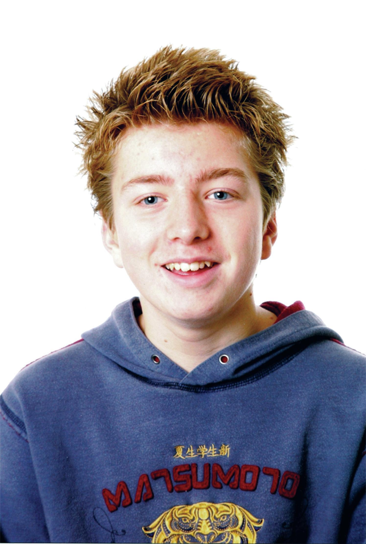 Portrett av en smilende ung med blå hettegenser.