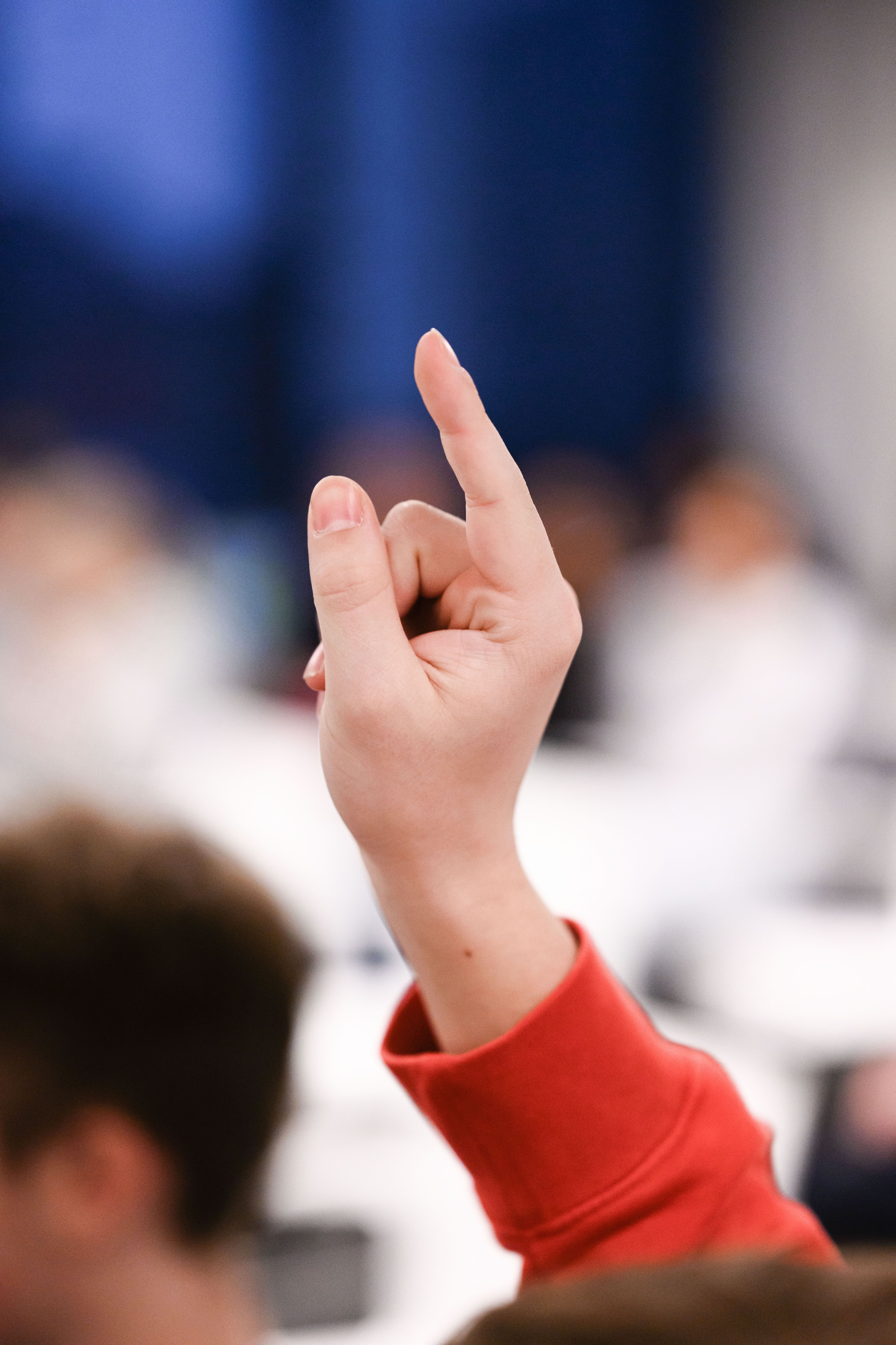 Raised hand with red sleeve. Blurred background.