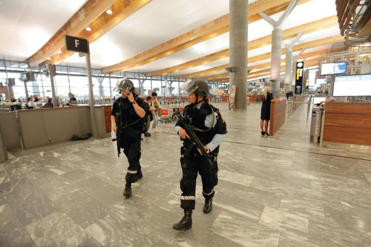 Two people in uniform and carrying weapons. Sign that says "F". Gray floor. White ceiling.