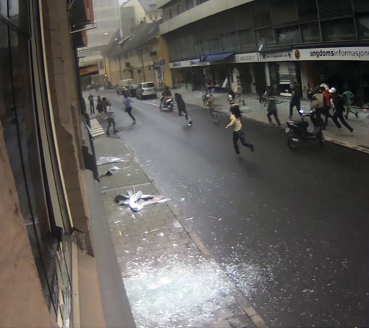 Group of people in Møllergata running towards Stortorget. Broken glass on the pavement. Screenshot from surveillance video