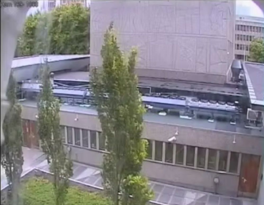 Picture of a building seen from a high angle. Three trees in front. 