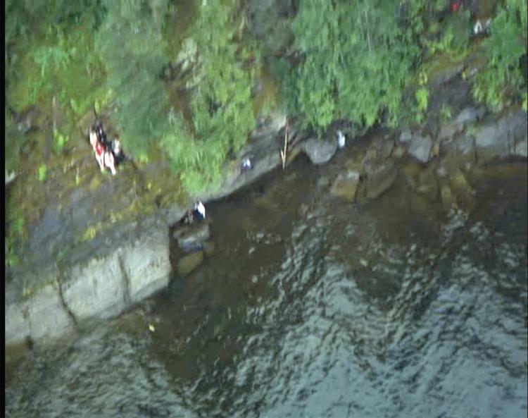  Aerial photo of people on rocks at the water's edge.