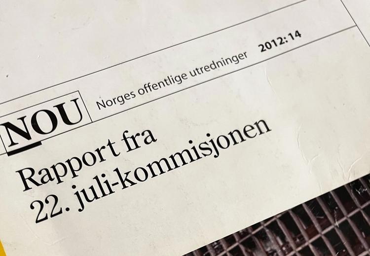  The front page of a report. The report is white with a yellow stripe. The cover image is of a damaged building with an ambulance worker and a police officer. Text: NOU Norway's public investigations 2012:14 Report from the 22th July commission