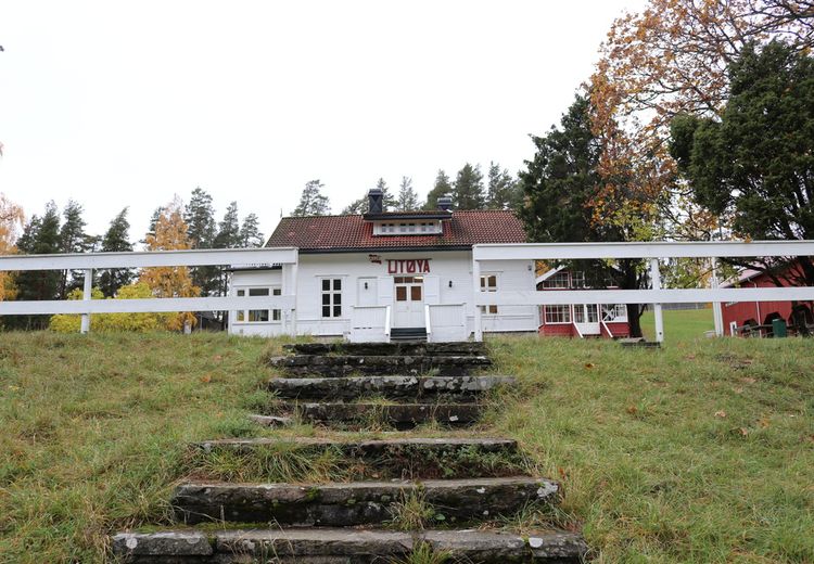 Hvit hus med rødt skilt med teksten "Utøya". Steintrapper.  