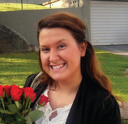 Picture of a smiling girl with flowers. Close-up picture. Lawn and a hous in the background