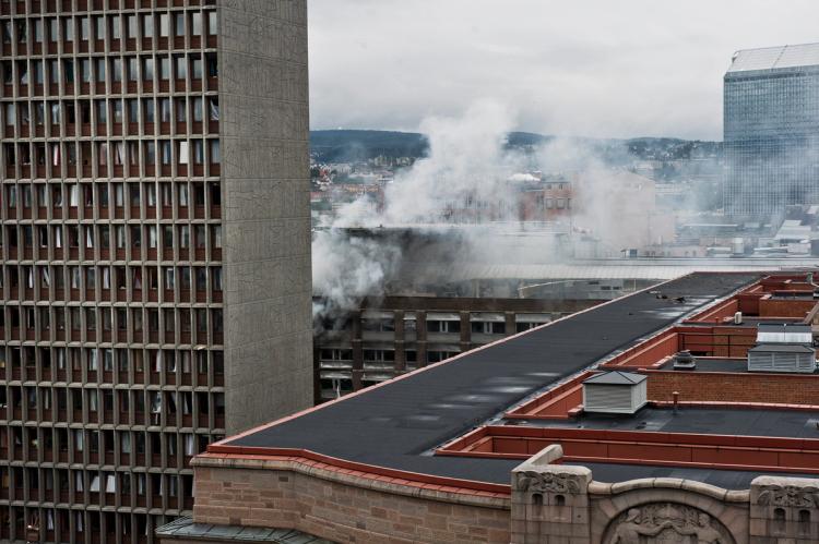 Bilde av tre bygninger. Røyk kommer ut fra en bygningene i bakgrunnen.