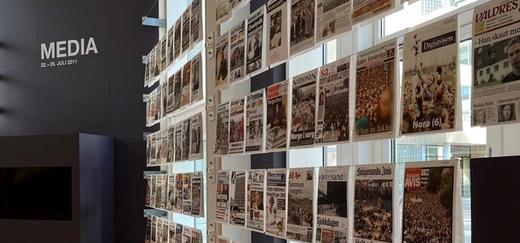 Flere avisforsider utstilt i 22. juli-senterets lokaler. Media står skrevet i stor skrift i bakgrunnen.