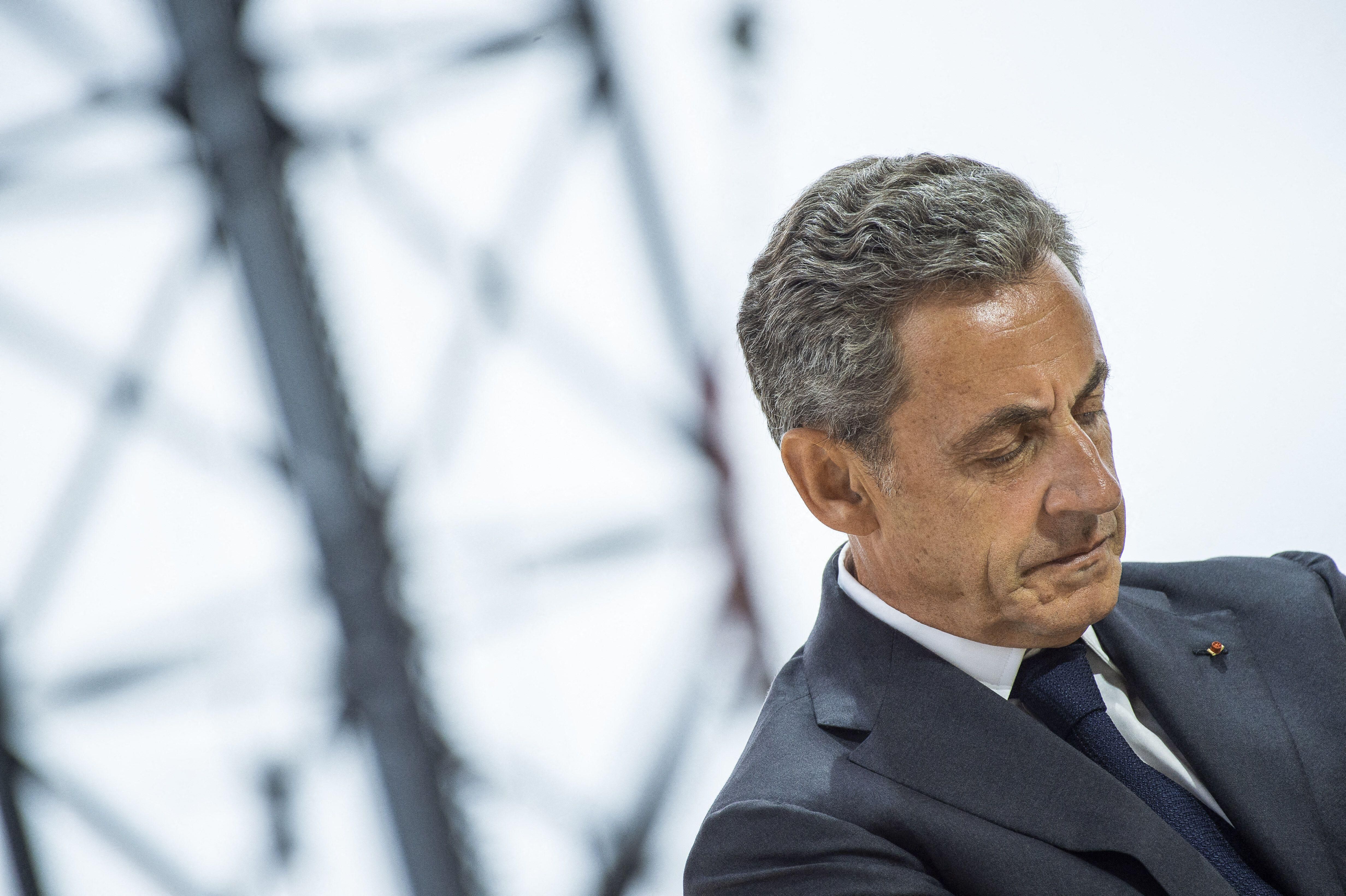 Former French President Nicolas Sarkozy, wearing a dark suit and tie, looks down pensively during a public appearance at the Medef summer meeting in Paris in 2019.