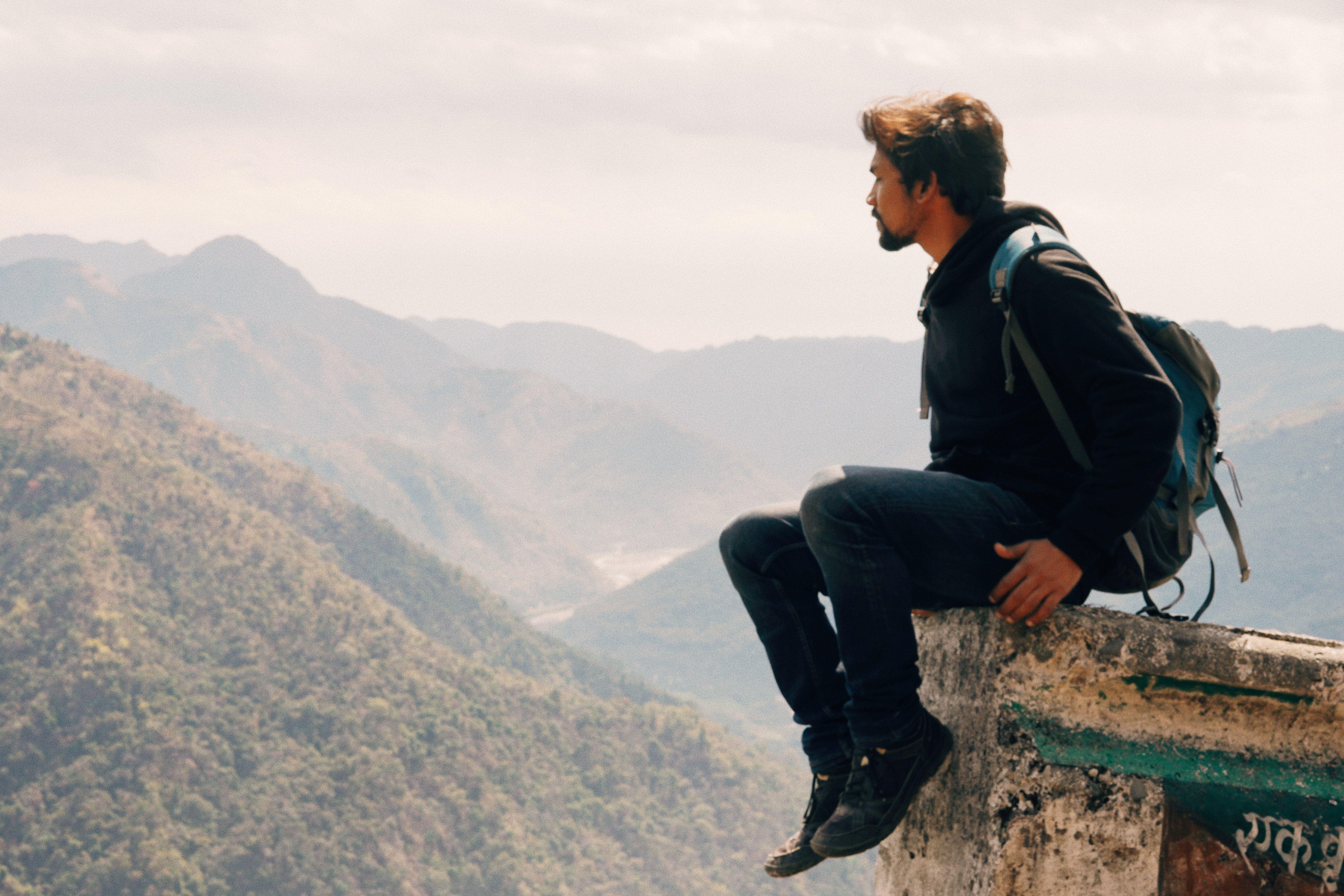 Man sitting on top of mountain overlooking valley