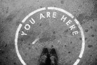 You are here text writing on ground in circle with feet standing in it