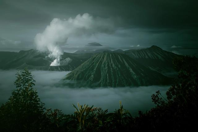 Erupting volcano in lush landscape