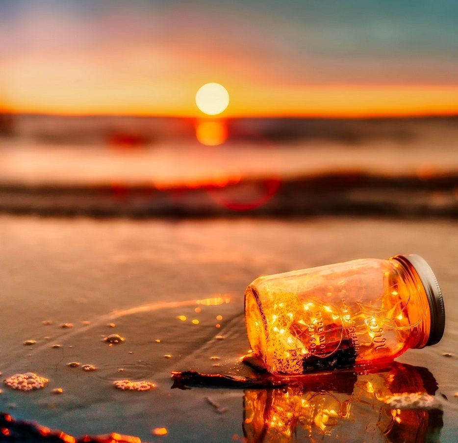 Jar on beach with sunset in background