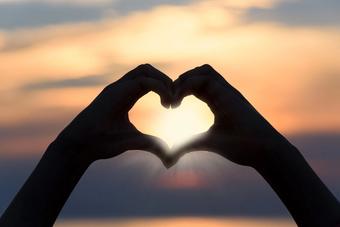Hand making a heart in sunset