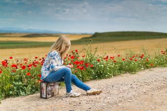 Woman sitting on side of the road with flowers