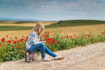 Woman sitting on side of the road with flowers