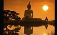 Buddhist statue in distance with sunset
