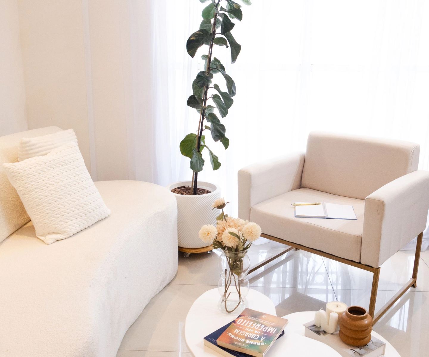 A pale, airy sitting room with white upholstery and a potted fig
