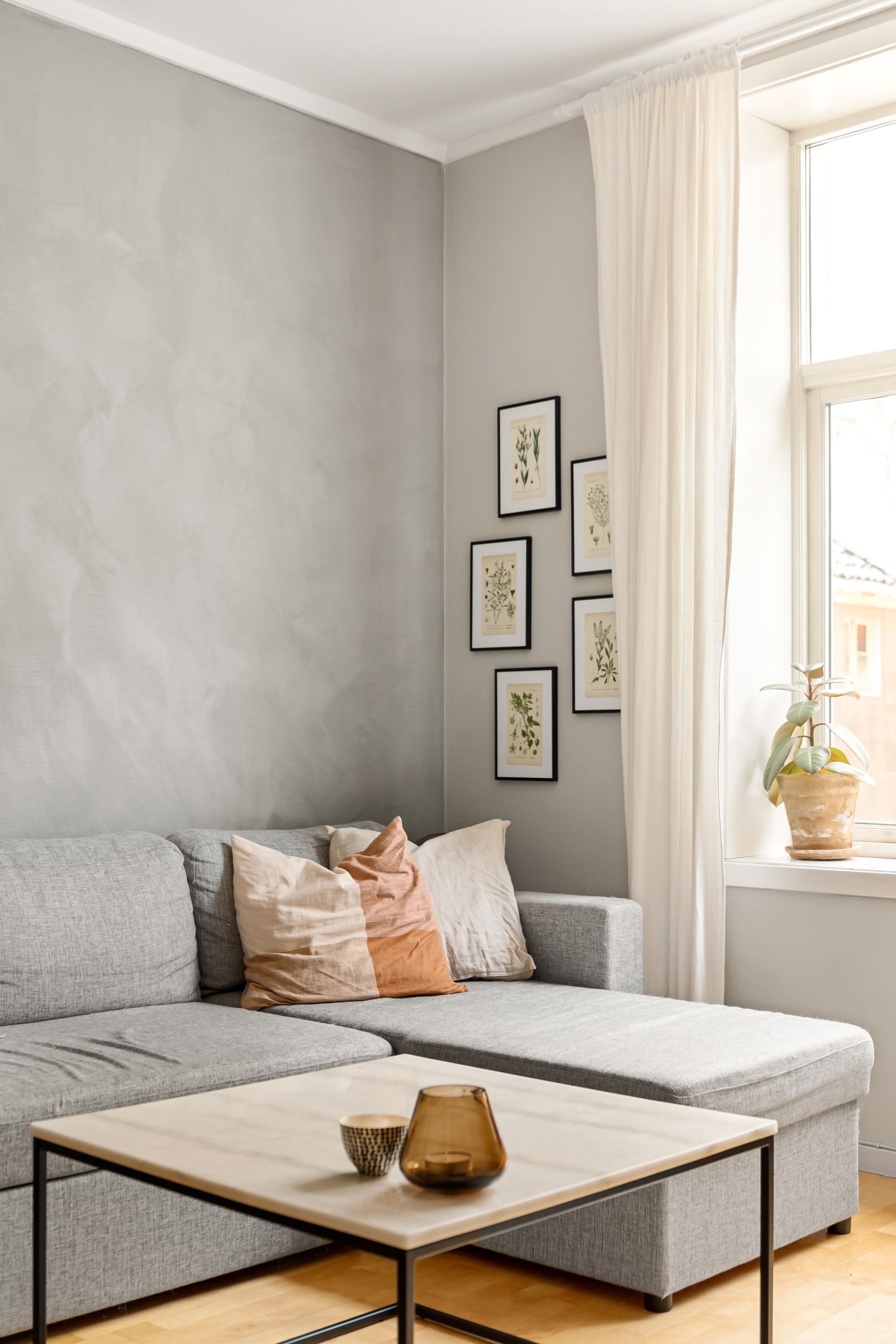 A cushioned window seat below framed prints, lit from the side