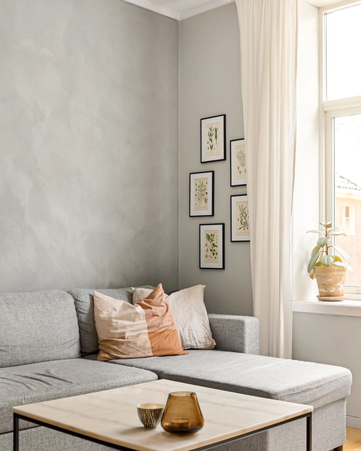 A cushioned window seat below framed prints, lit from the side
