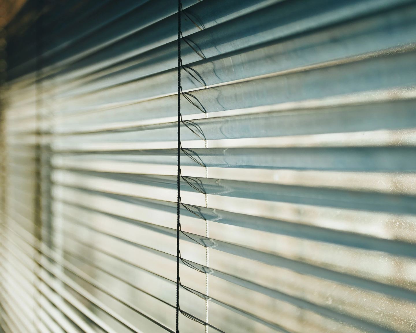 Close detail of blade edges and the tilt mechanism of a slatted blind