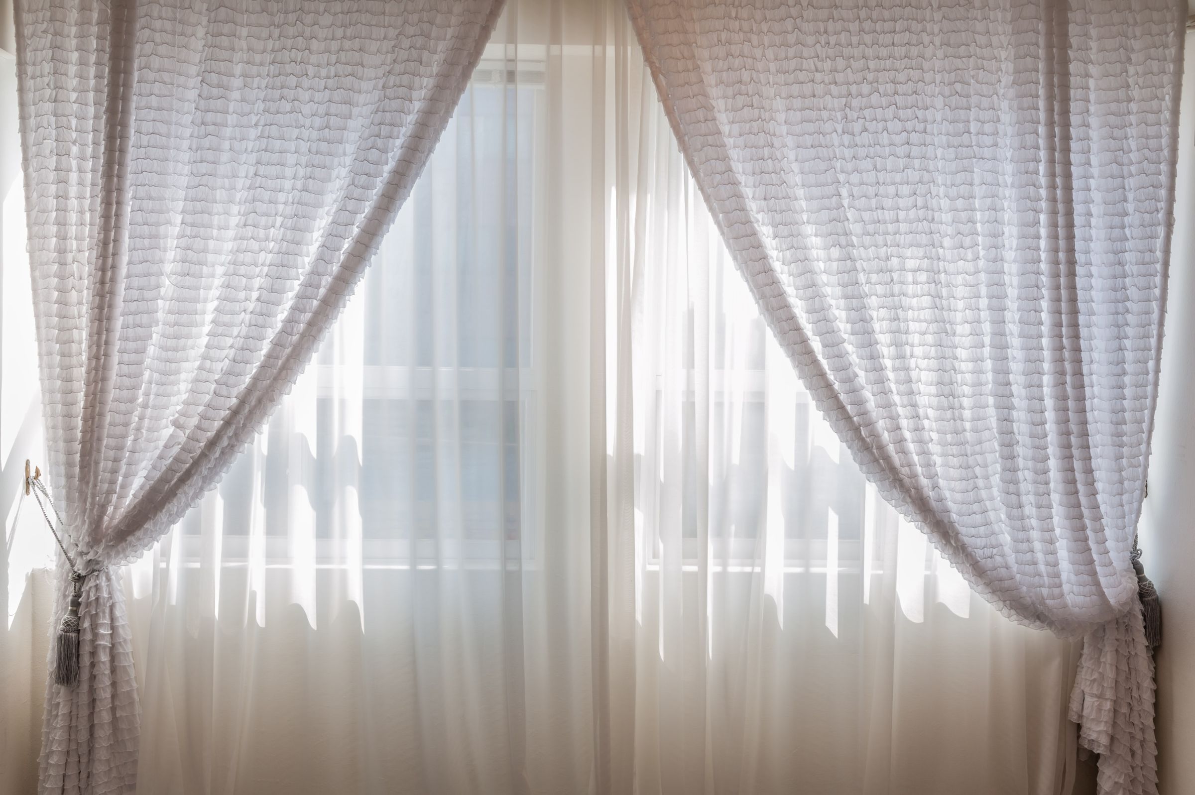 Soft draped sheer fabric diffusing daylight across a window