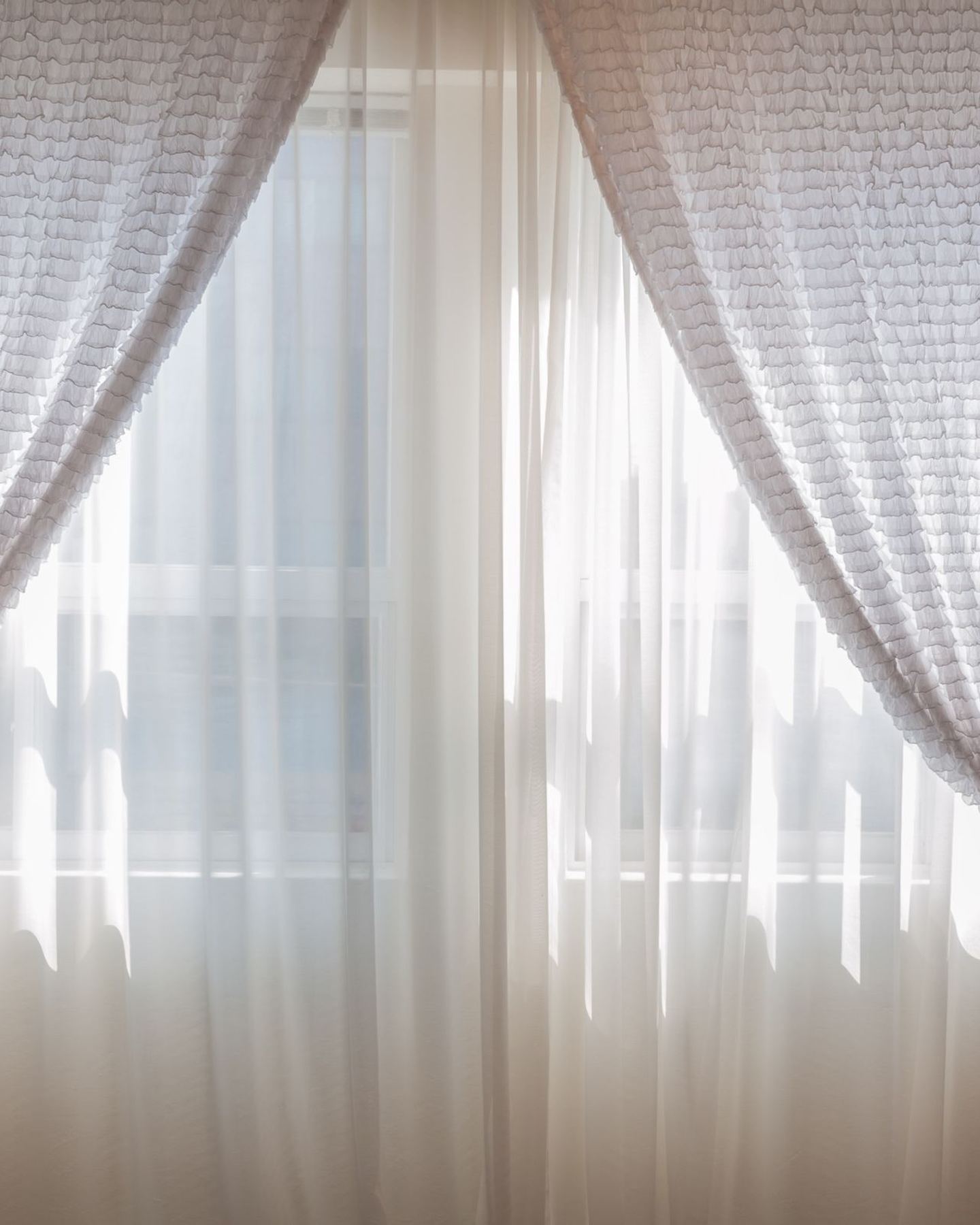 Soft draped sheer fabric diffusing daylight across a window