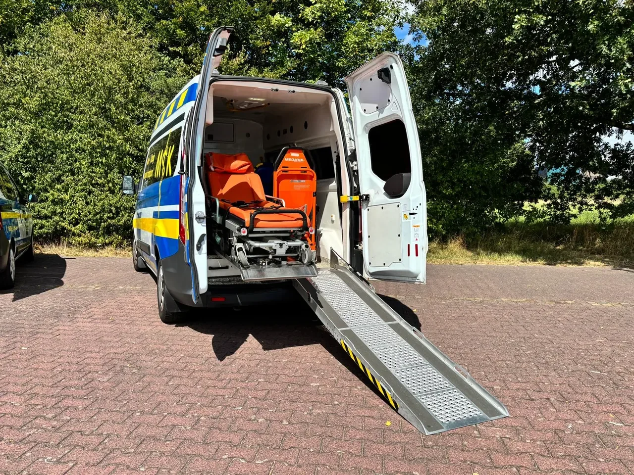 Geöffneter Krankentransporter mit ausgeklappter Rampe und Tragestuhl