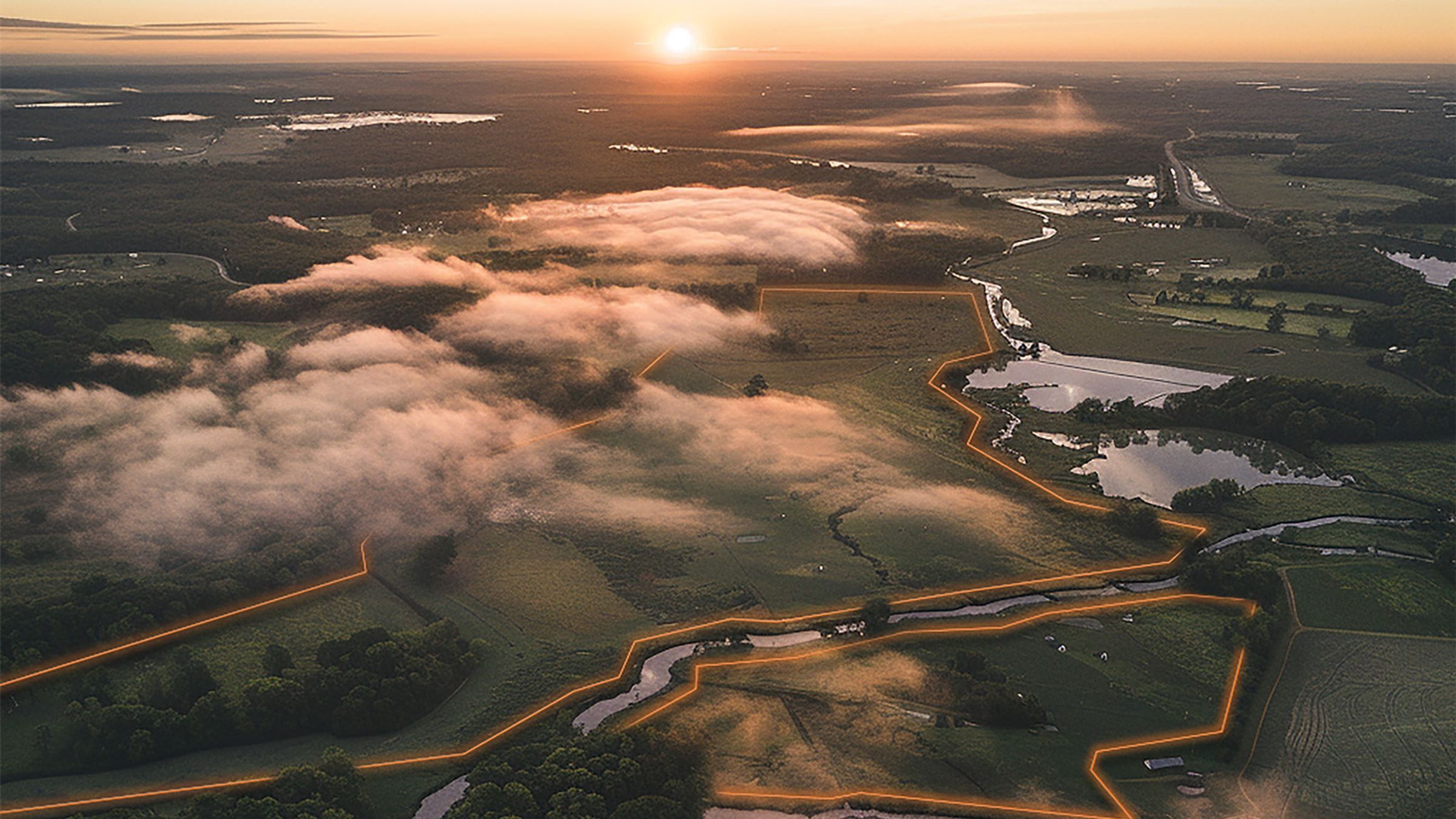Aerial view of pasture at sunrise with a virtual fence boundary drawn in orange