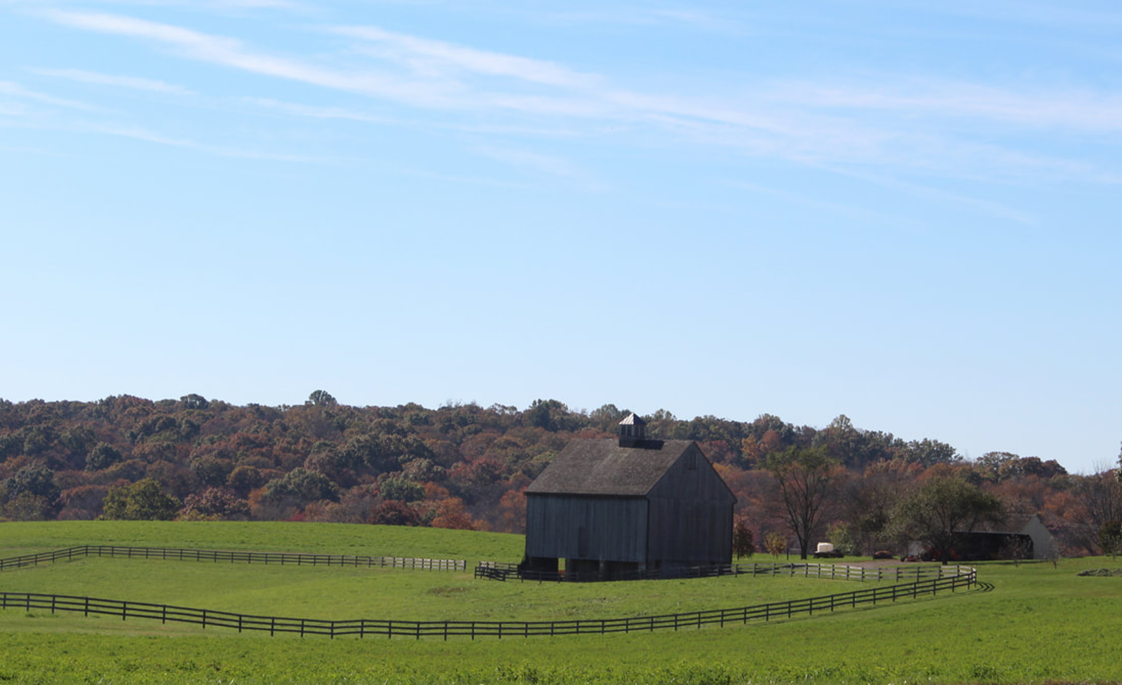Pennsylvania historic barn with split rail fence and trees and sky in background 
