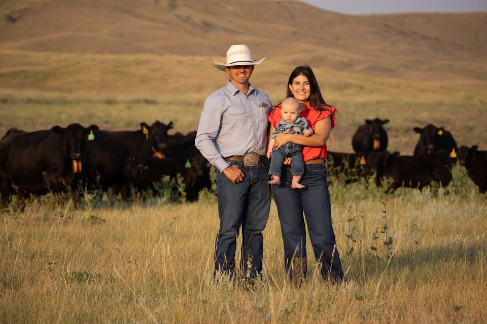 Rancher family stands in field in front of cows with eShepherd neckbands