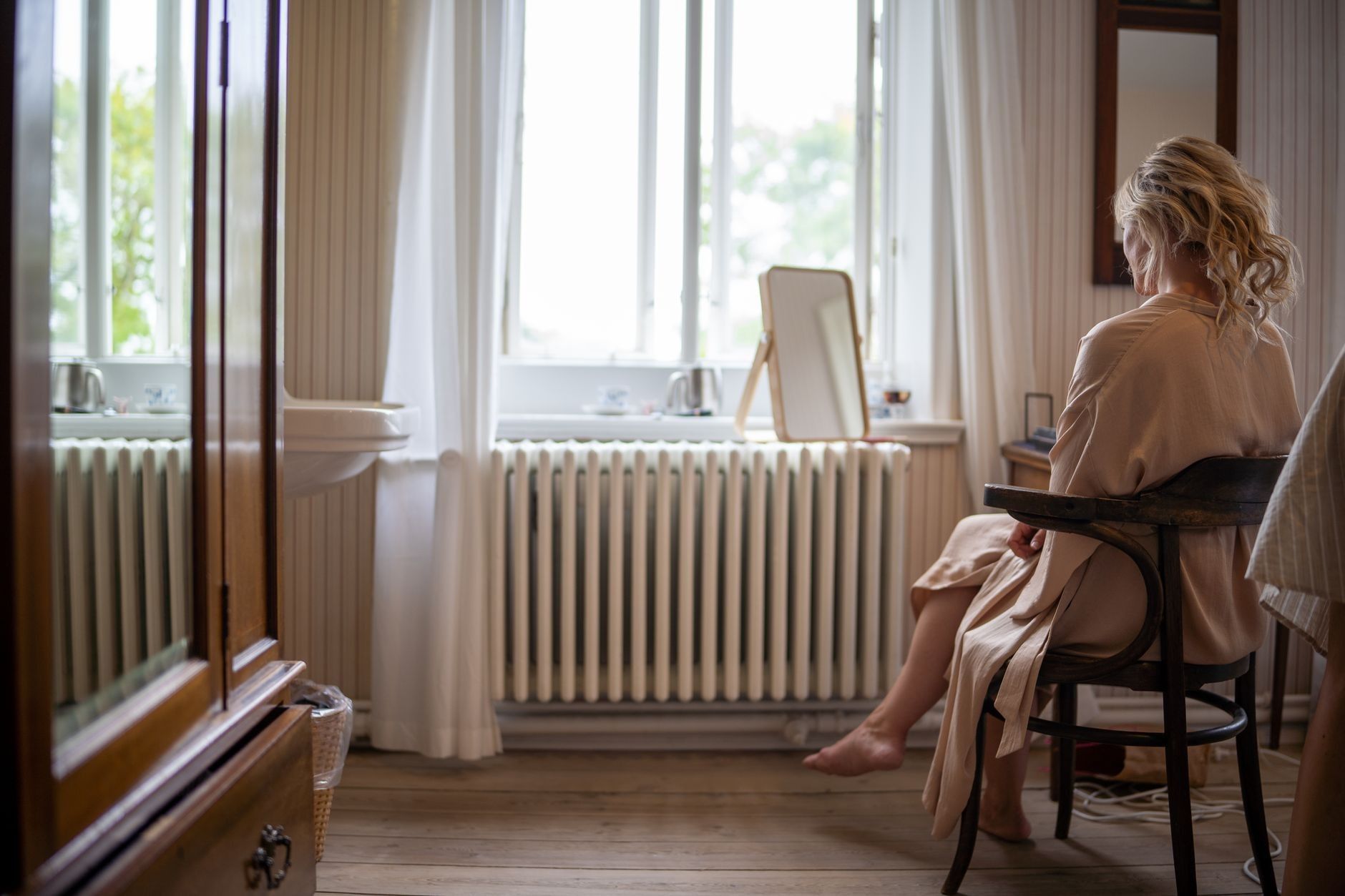 Frau in Wohnung von hinten auf Stuhl sitzend