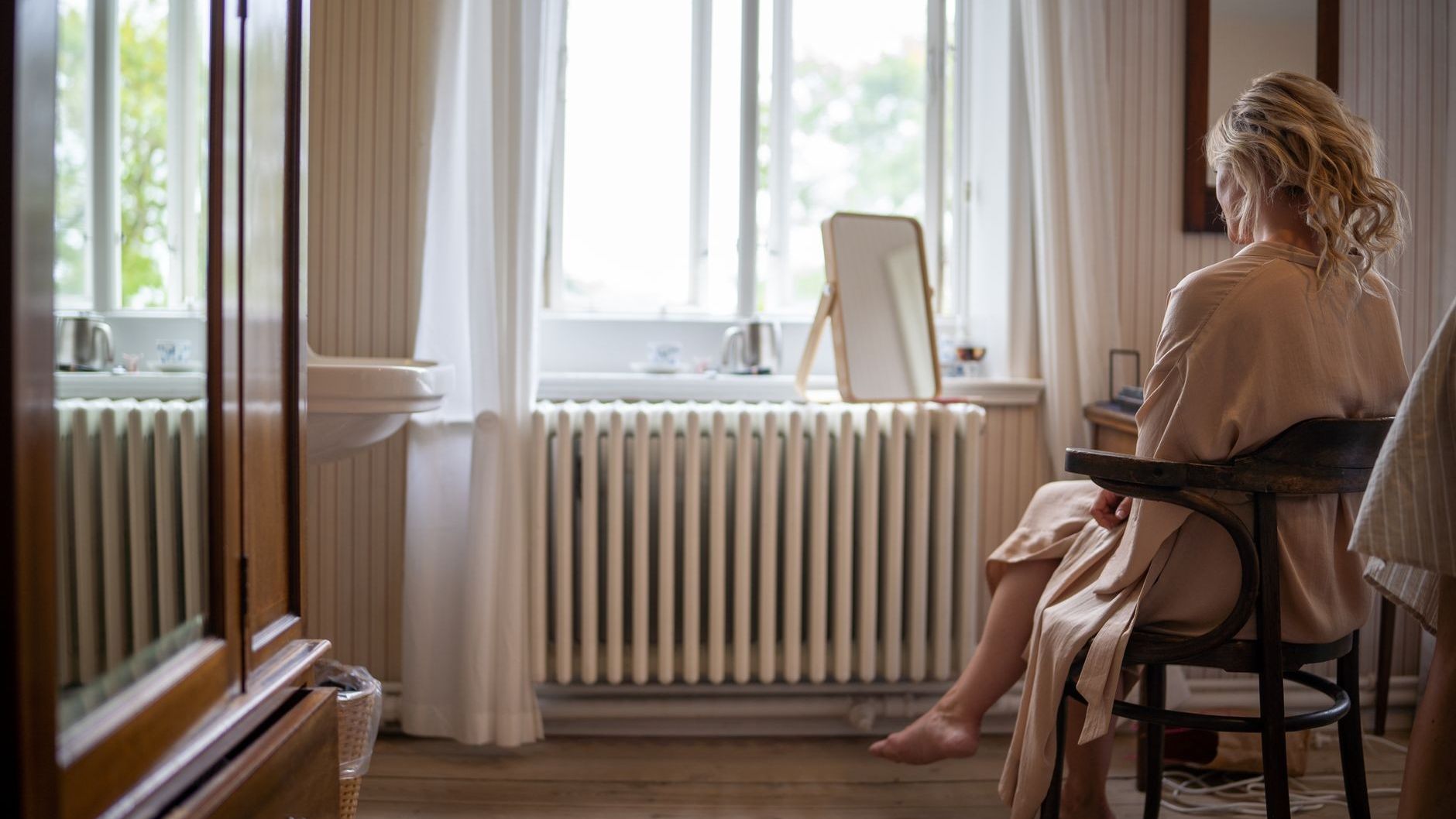Frau in Wohnung von hinten auf Stuhl sitzend