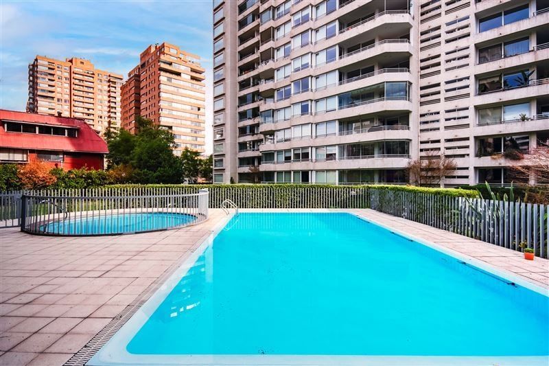 Piscina exterior del condominio con edificios al fondo