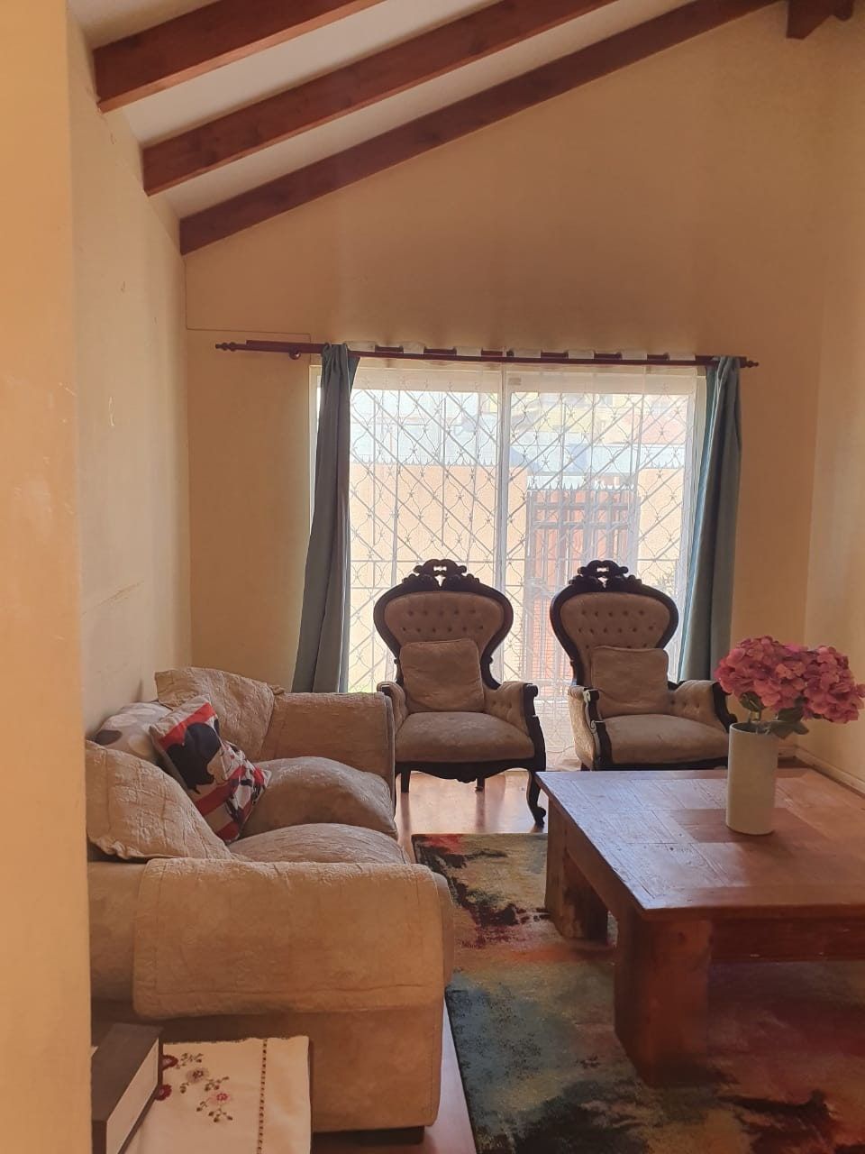 Living con sofá, dos sillones estilo clásico, mesa de centro y ventana hacia el patio enrejado.