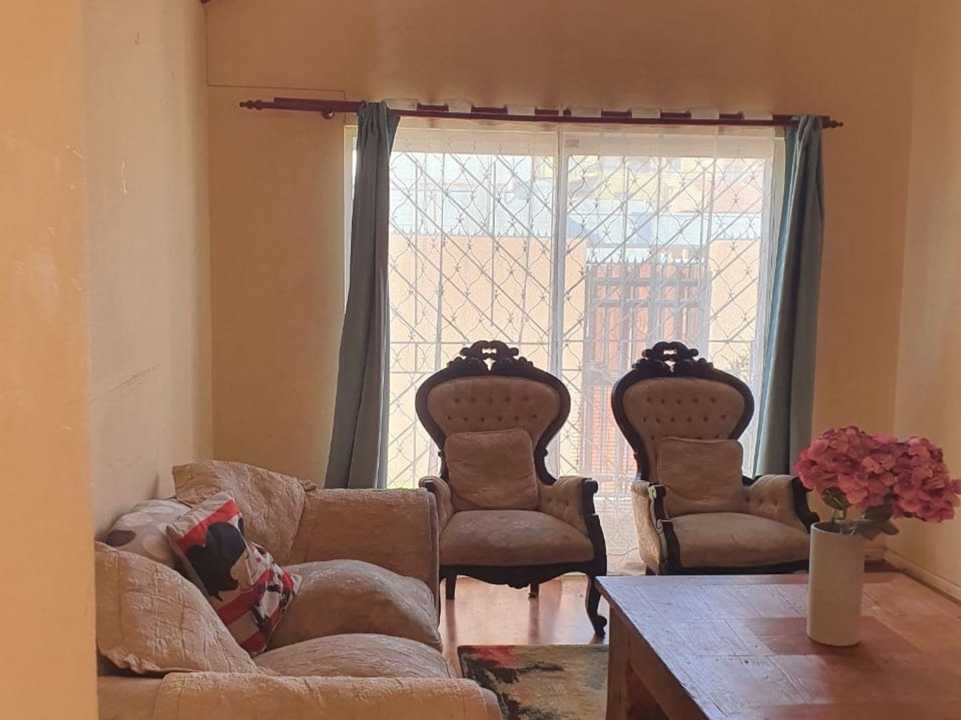Living con sofá, dos sillones estilo clásico, mesa de centro y ventana hacia el patio enrejado.